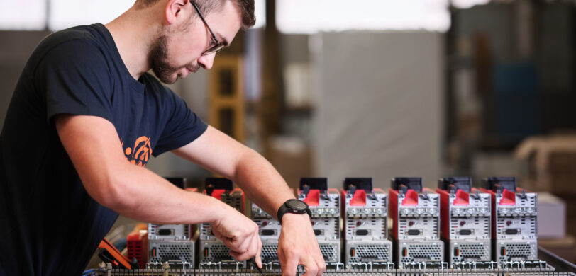 Ein Techniker führt Elektro Arbeiten an einer komplexen Schalttafel durch, bei der Schaltschränke mit Verkabelungssystemen verbunden sind. Die Installation erfolgt im Industrie Bereich und umfasst Komponenten, die auch in Mittel- und Hochspannungsanlagen sowie bei Glasfaserarbeiten und Erneuerbaren Energien eingesetzt werden.