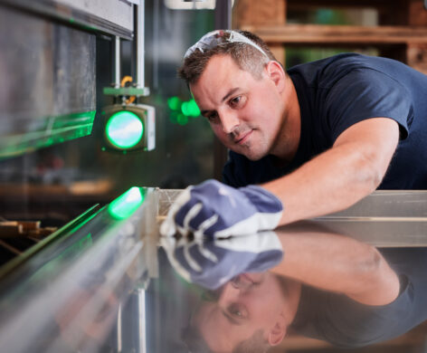 Ein erfahrener Metallbauer prüft sorgfältig die Maßarbeit an einem Blech in der Fertigung. Die präzise Blechverarbeitung erfolgt mit hoher Qualität durch professionelle Planung, Konstruktion und Produktion.