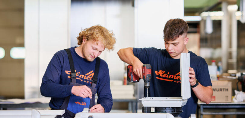 Zwei Facharbeiter im Metallbau führen Maßarbeit an Blechkomponenten durch. Sie arbeiten konzentriert mit Werkzeugen an der Fertigung und Montage in einer modernen Werkstatt. Die Planung, Konstruktion und Produktion der Bauteile erfolgt mit hoher Qualität und langjähriger Erfahrung in der Blechverarbeitung.