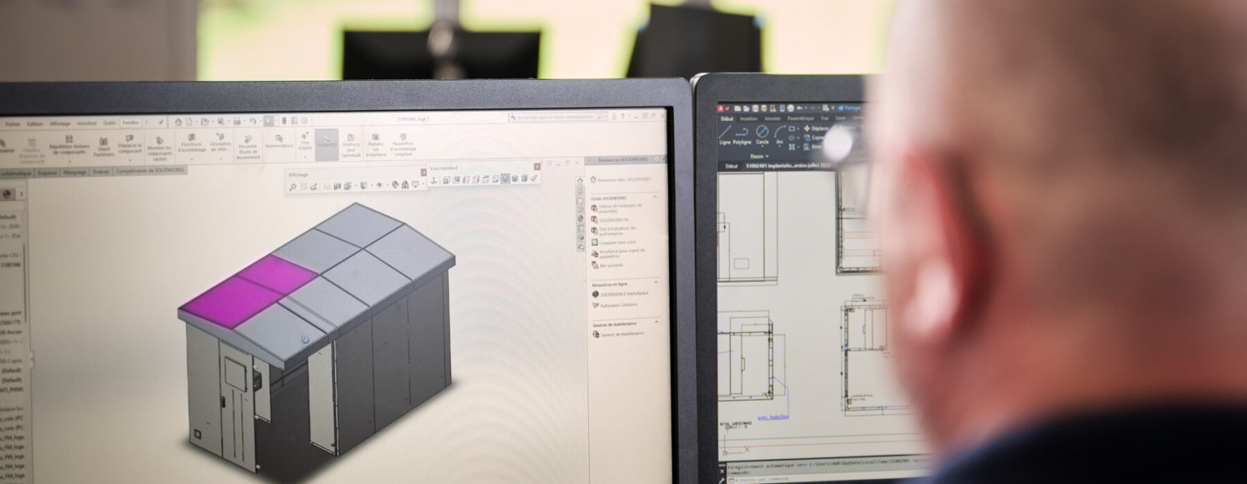 Ein erfahrener Projektmanager arbeitet an zwei Bildschirmen mit durchdachten Plänen und Dokumentationen zur Entwicklung eines Gebäudemodells. Als zentraler Ansprechpartner nutzt er seine Kompetenz für eine transparente und lösungsorientierte Planung im Projektmanagement.