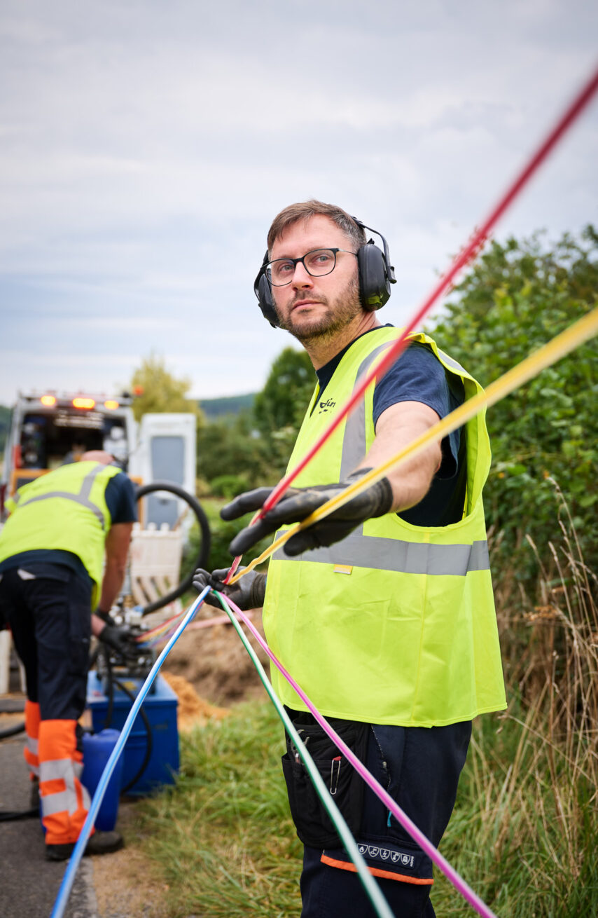 Techniker ziehen farbige Kabel für Mittelspannungsanlagen und Niederspannungsverteilung im Freien