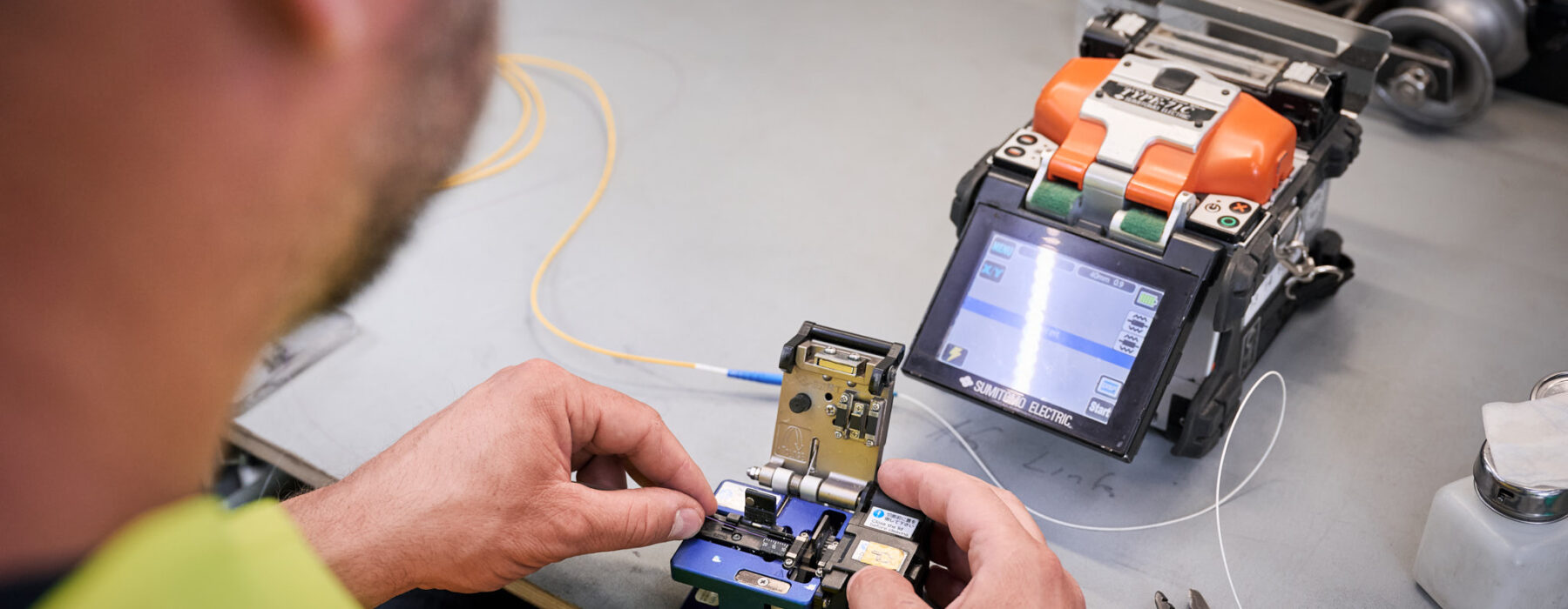 Techniker bedient Fusionsspleißmaschine für Stromnetzinfrastruktur und Mittelspannungsanlagen