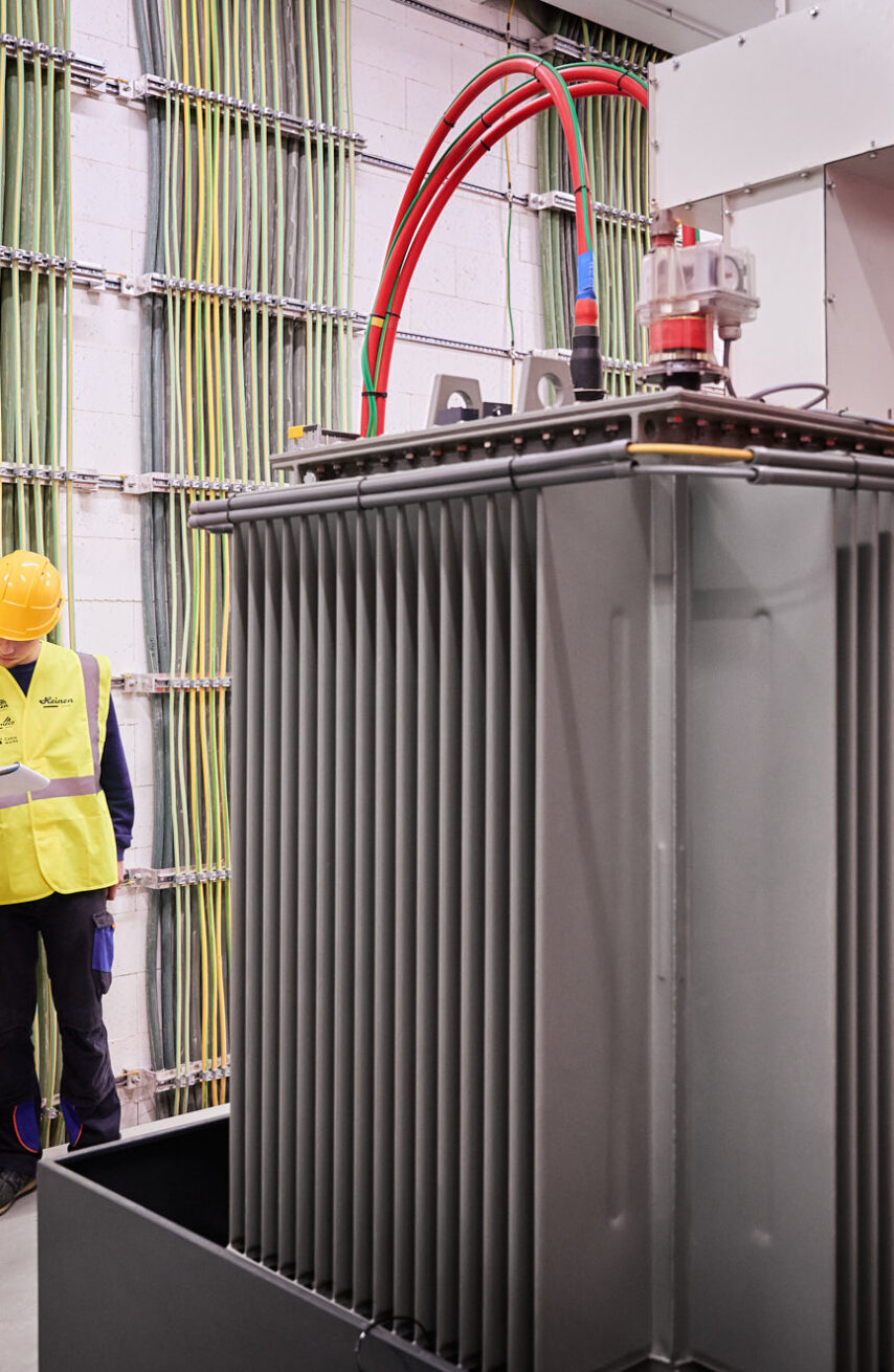 Techniker prüfen Elektrotechnik mit Transformator und Glasfaser Leitungen in Industriehalle