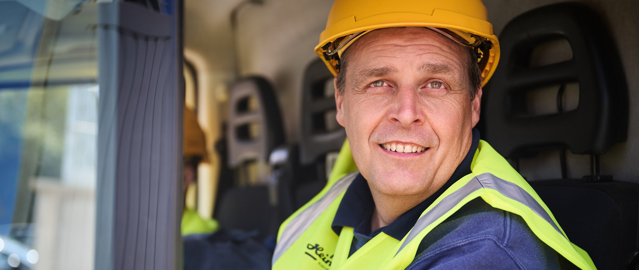 Bauarbeiter mit Helm und Warnweste als zentraler Ansprechpartner im Fahrzeug