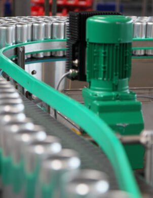 Eine Produktionsanlage mit einem Förderband, auf dem zahlreiche Aluminiumdosen transportiert werden. Die Anlage ist Teil der Industrie und zeigt Elektrotechnik im Einsatz. Solche Produktionsanlagen sind essenziell für verschiedene Sektoren, darunter Geschäft, Einzelhandel und Großhandel. Sie tragen zur Infrastruktur bei und sind auch in öffentlichen Gebäuden und öffentlichen Bauprojekten relevant.