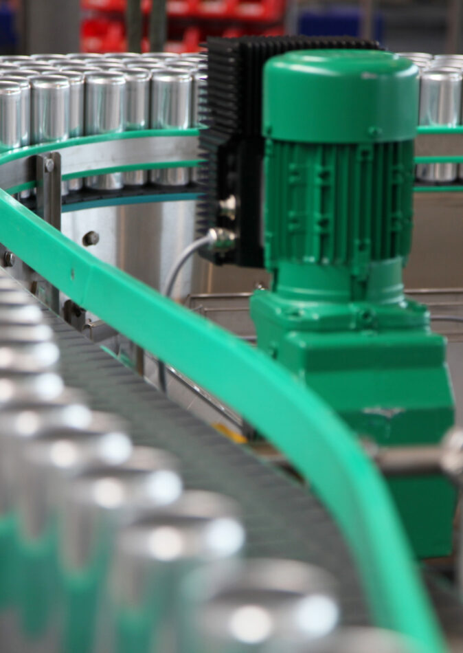 Eine Produktionsanlage mit einem Förderband, auf dem zahlreiche Aluminiumdosen transportiert werden. Die Anlage ist Teil der Industrie und zeigt Elektrotechnik im Einsatz. Solche Produktionsanlagen sind essenziell für verschiedene Sektoren, darunter Geschäft, Einzelhandel und Großhandel. Sie tragen zur Infrastruktur bei und sind auch in öffentlichen Gebäuden und öffentlichen Bauprojekten relevant.